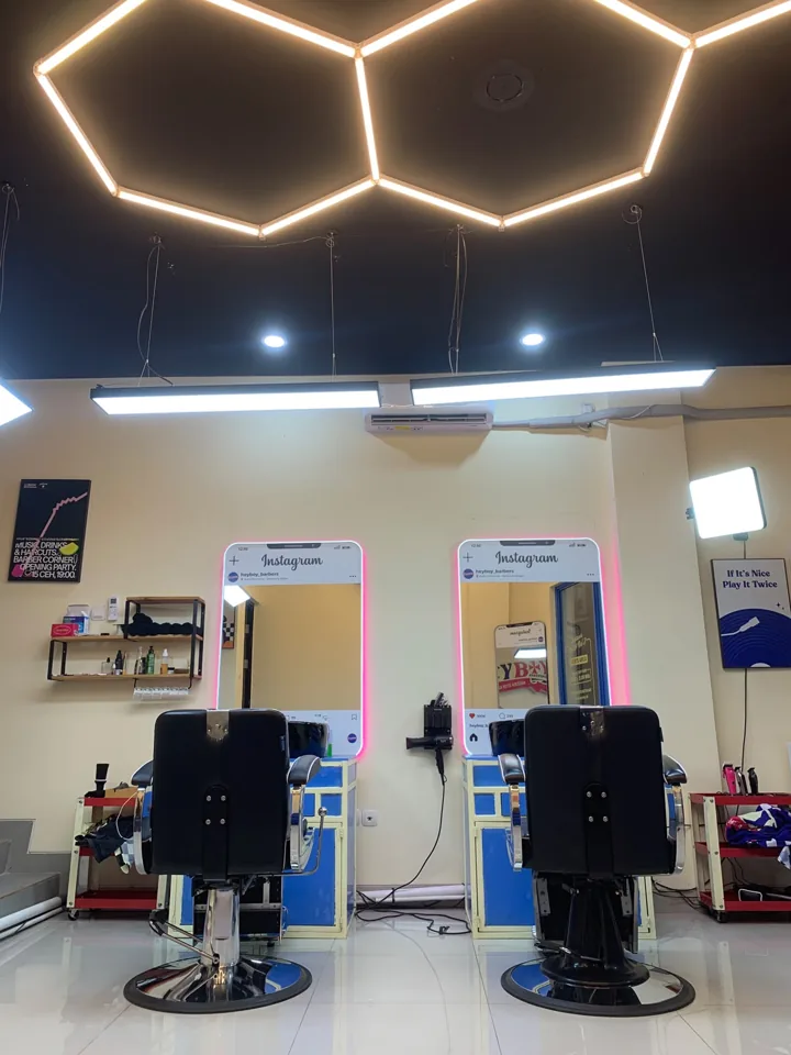 Interior HEYBOY dengan kursi barber, kabinet biru, dan lampu plafon heksagonal
